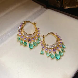 Detailed view of gold hoop earrings with purple and green zircon teardrop pendants.