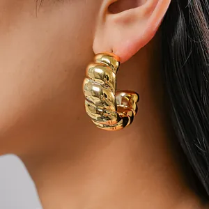 Nahaufnahme eines goldenen strukturierten Creolen-Ohrrings mit glänzendem Rippendesign.