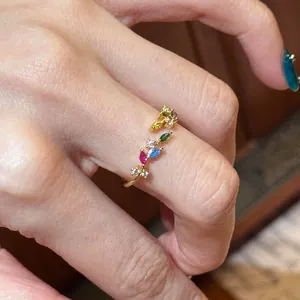 Eleganter Goldring mit bunten Markasit-Steinen im Weizenmuster am Finger getragen