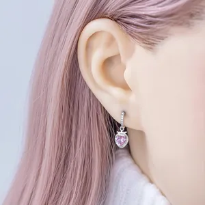 Boucle d'oreille délicate avec pendentif cœur fraise rose portée par un mannequin