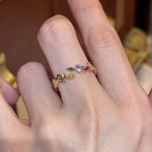 Detailansicht eines zierlichen goldenen Ährenrings mit bunten Edelsteinen am Finger