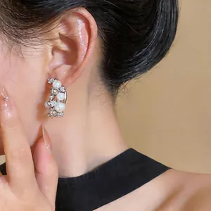 Elegant French style pearl and zircon cluster earrings shown in detail on model ear
