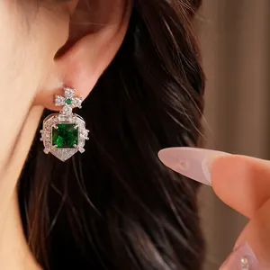 Gros plan de boucles d'oreilles vintage en argent avec un grand zircon vert carré