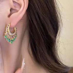 Close-up view of luxury gold hoop earrings with purple and green zircon droplets.