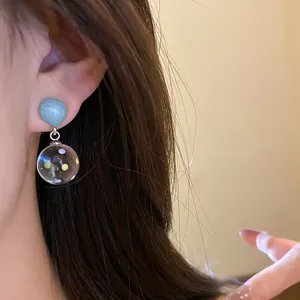 Detailed close-up view of blue resin stud earrings with colorful polka dot drop pendant