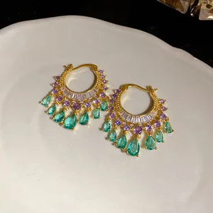 Detailed macro view of luxury gold zircon hoop earrings with green waterdrop pendants