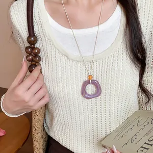 Primo piano di una collana con ciondolo geometrico in acrilico viola minimalista.
