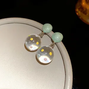 Detail view of resin stud earrings with colorful dots inside transparent sphere