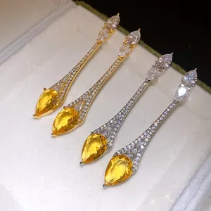 Gros plan de boucles d'oreilles pendantes en or et argent avec pierres jaunes en forme de poire