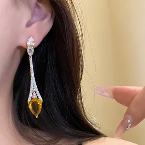 Gros plan d'une élégante boucle d'oreille goutte dorée avec zircon ambre étincelant