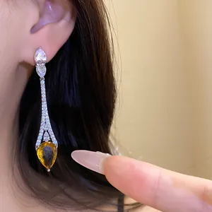 Gros plan de boucles d'oreilles pendantes en plaqué or 18 carats avec zircons blancs.