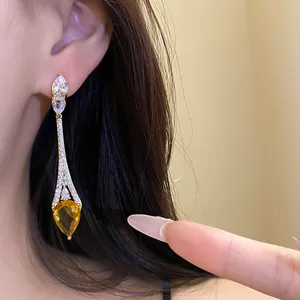 Vue détaillée d'élégantes boucles d'oreilles longues en or 18 carats et zircon jaune