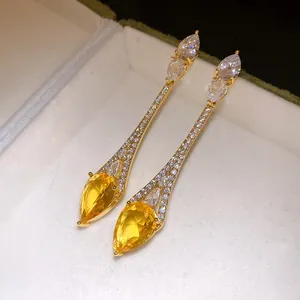 Gros plan de boucles d'oreilles pendantes plaquées or 18k avec zircons jaunes en goutte.