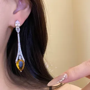 Gros plan d'une élégante boucle d'oreille goutte en or 18 carats avec zircone jaune