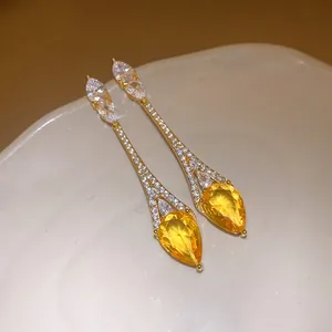 Détail montrant l'éclat des boucles d'oreilles plaquées or avec zircon jaune en goutte d'eau.