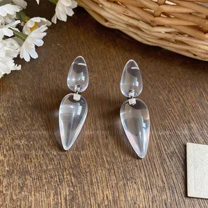 Detailed macro view of clear resin water drop earrings with silver needle posts.