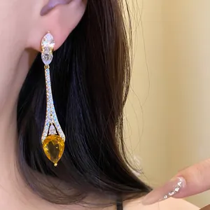 Vue détaillée de boucles d'oreilles pendantes avec un zircon ambré en forme de goutte.