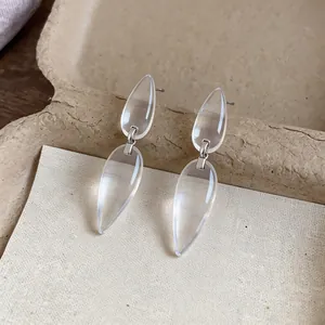 Close-up detail of minimalist transparent resin water drop earrings with silver needle pins