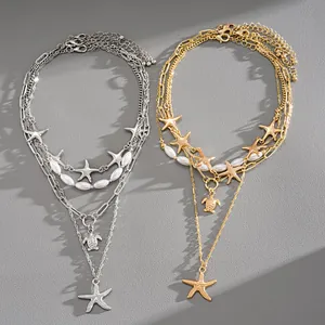 Set of gold and silver layered necklaces with starfish, turtle charms and pearls.