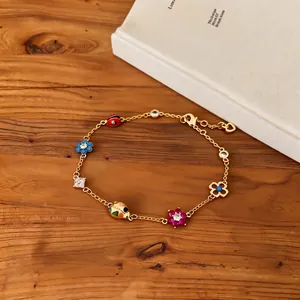 Detail view of a vintage gold charm bracelet with enamel flowers and ladybugs