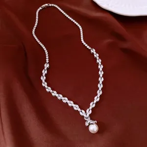 Elegant zircon and pearl pendant necklace displayed on a luxurious red silk background