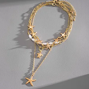 Detailed macro view of a layered gold necklace featuring starfish, turtle charms and pearls