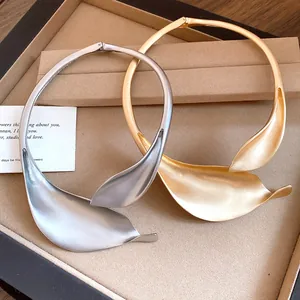 Close-up macro view of matte gold and silver leaf petal choker necklaces on jewelry display