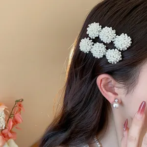 Close-up detail of a model wearing elegant French-style pearl cluster hair clips on her hair