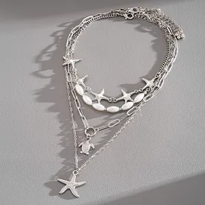 Close-up detail of a multi-layer silver necklace featuring starfish and sea turtle charms
