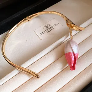 Macrodetail van een gouden tulpenhanger aan een choker in een sieradendoosje
