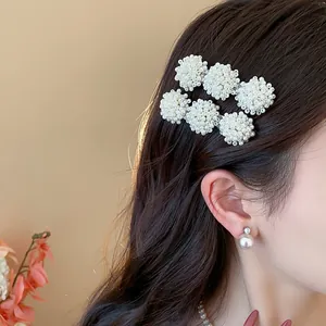 Elegant white pearl ball hair clips worn on brown wavy hair for a stylish look