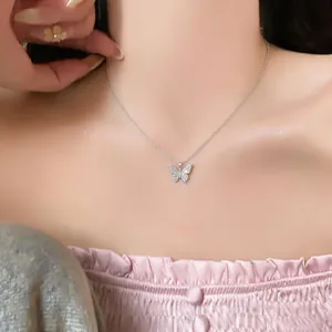 Detailed macro view of a sparkling zircon butterfly pendant on a refined 18k gold plated necklace.