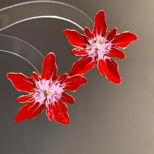 Detailed macro shot of glossy red enamel flower earrings with intricate gold-toned edges