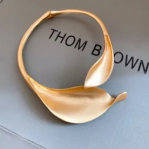 Macro detail of a vintage matte gold floral choker featuring an elegant overlapping leaf design