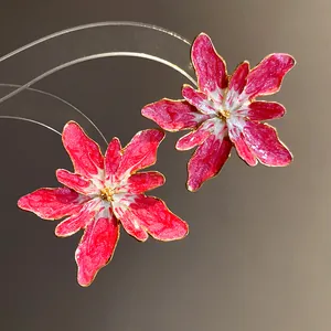 Detailed close-up of vibrant pink and white enamel flower earrings with gold trim