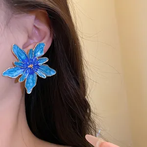Close-up of a blue enamel flower ear stud worn on ear, elegant vacation jewelry