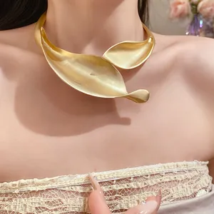 Close-up of matte gold statement leaf collar necklace worn by female model in detail view