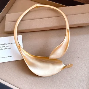 Close-up of matte gold floral leaf choker with minimalist high-end vintage texture