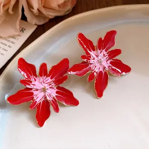 Macro detail view of red and pink enamel flower stud earrings with elegant gold trim