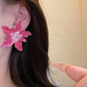 Detailed close-up of pink enamel flower stud earring with elegant gold metal edges