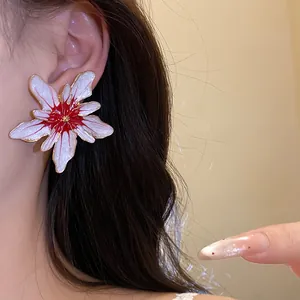 Detailed macro view of white and red enamel flower stud earring with golden metallic edges