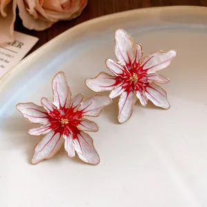 Close-up detail of elegant white and red enamel flower stud earrings with gold metallic edges