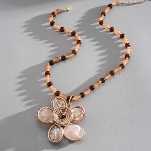 Dettaglio di una collana vintage di perle di cristallo con ciondolo a fiore in filo