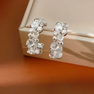 Primo piano dei dettagli degli orecchini a cerchio a C in argento con zirconi lucenti