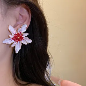Close-up of elegant flower stud earring with red center and glitter finish worn on ear