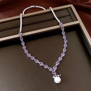 Detailed macro view of an elegant zircon necklace with purple leaves and a pearl drop