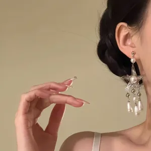 Detailed view of elegant silver starfish tassel earrings with hanging pearls on model
