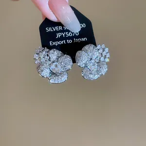 Detailed macro view of sparkly silver flower stud earrings with clear zircons