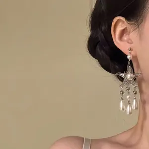 Detailed shot of silver starfish tassel earrings with elegant pearls worn by model.