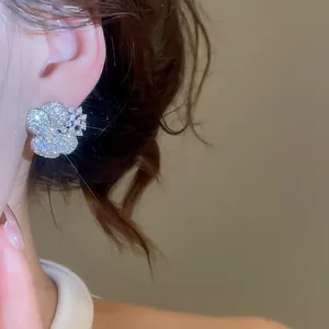 Detailed view of shimmering flower stud earring with sparkling cubic zirconia on ear